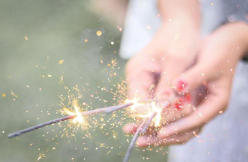 Midsection of woman holding sparklers outdoors