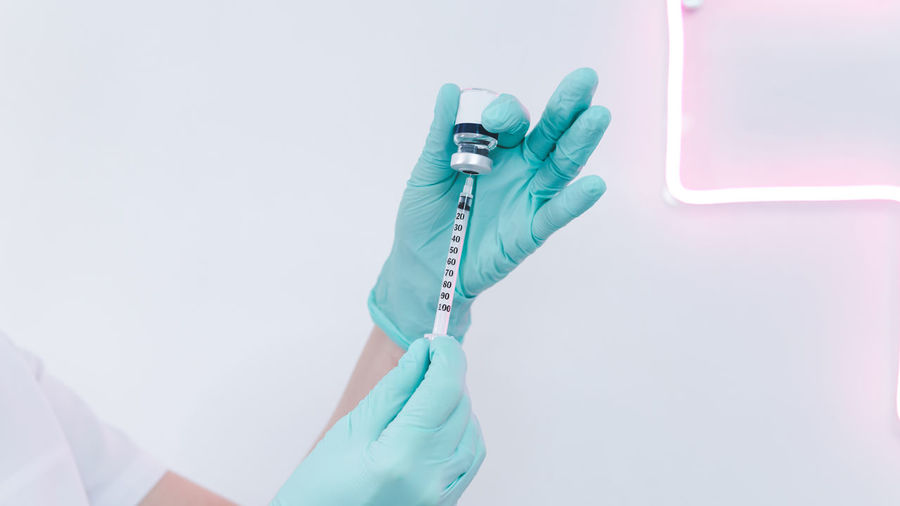 Cropped hands of doctor holding syringe and vial