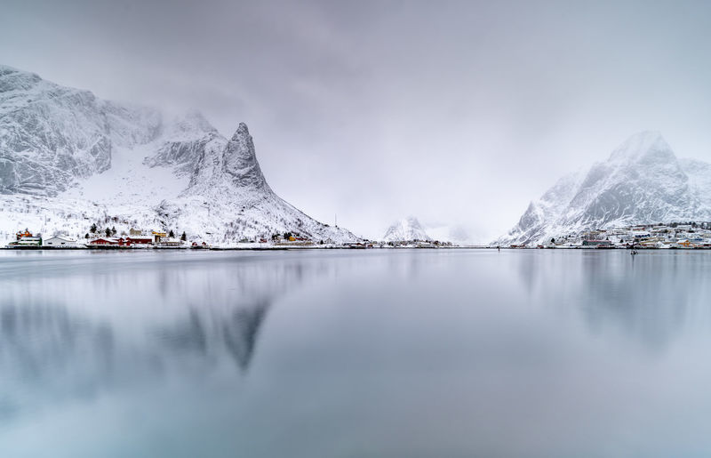 Scenic view of lake by snowcapped mountains against sky