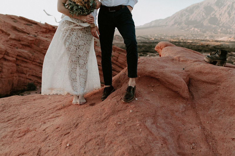 Low section of bride and groom standing on rock formation