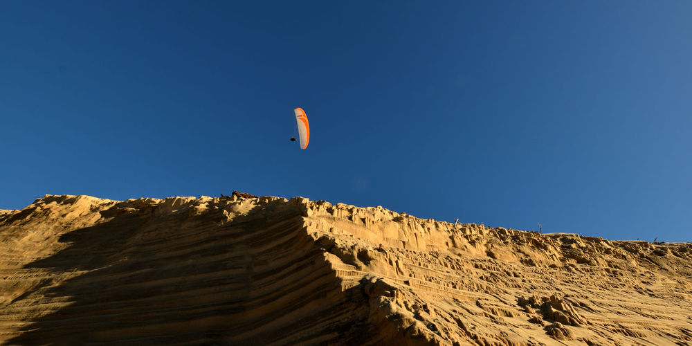 Person paragliding against clear blue sky