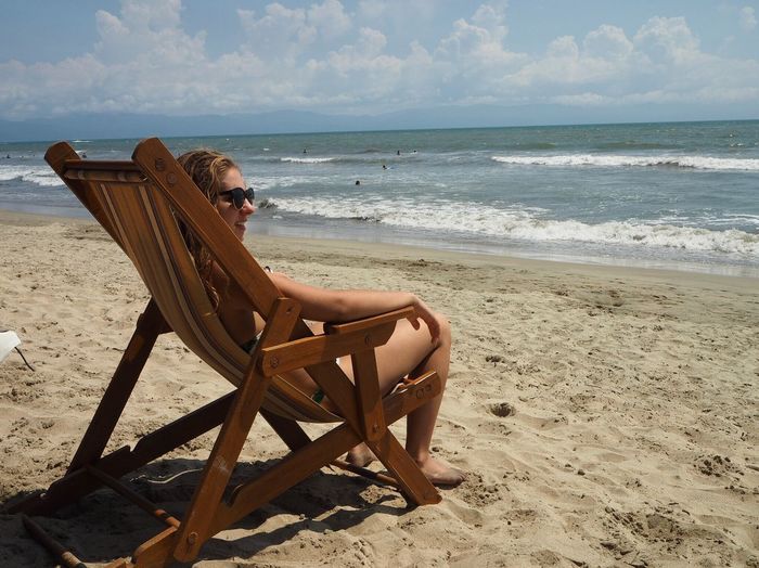 Chair on beach against sky