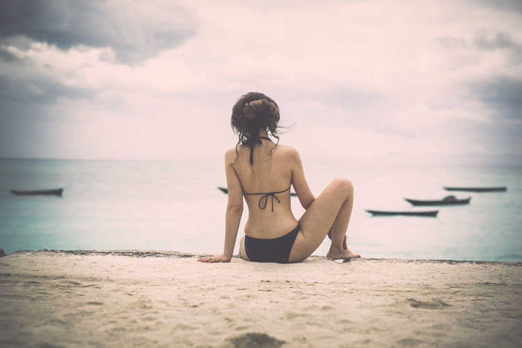 Rear view full length of sensuous woman in bikini at sandy beach