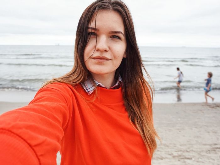 Portrait of young woman against sea at beach