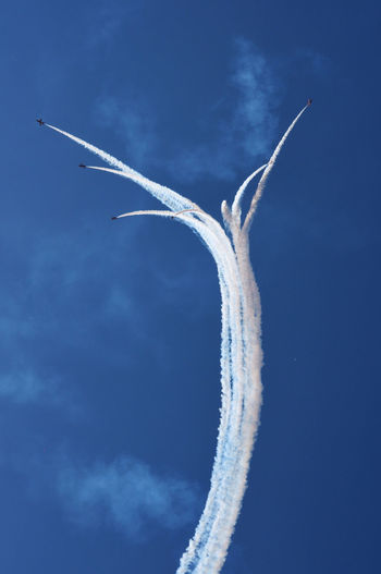Low angle view of airshow against blue sky