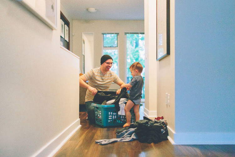 Father and son holding laundry at home
