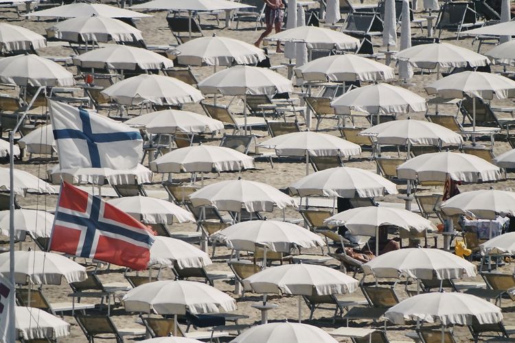Low angle view of flags against beach umbrellas 
