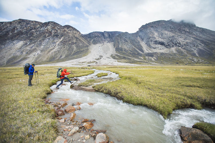 Backpackers cross rushing river at a narrow point, akshayak pass.