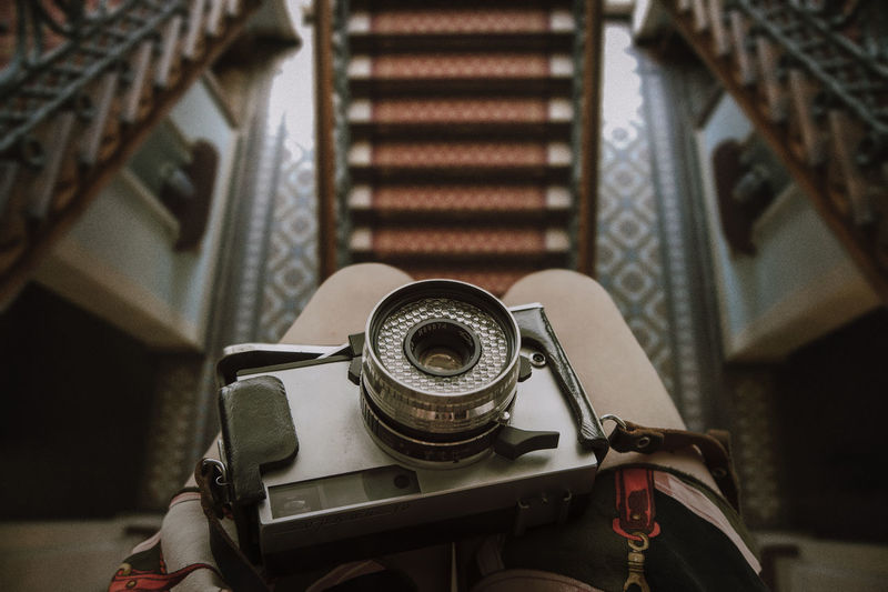 Midsection of person with camera sitting over staircase