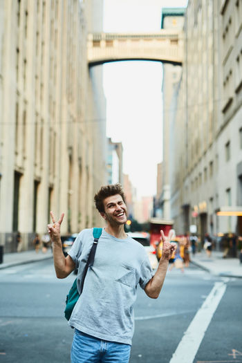 Young man gesturing peace sign while standing in city