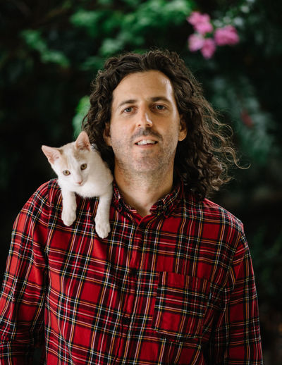Portrait of man with cat on shoulder outdoors