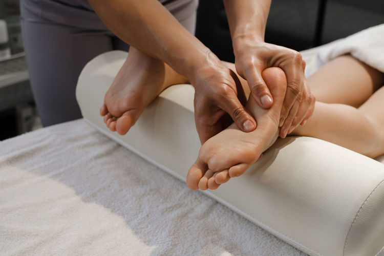 Child foot massage treatment by professional massage therapist in spa resort. stress relief 