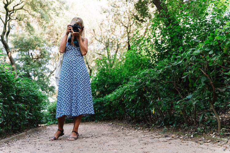 Woman in blue dress standing while taking a picture in a park
