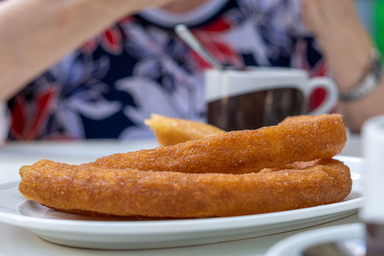 Close-up of some traditional churros, with an out-of-focus person in the background