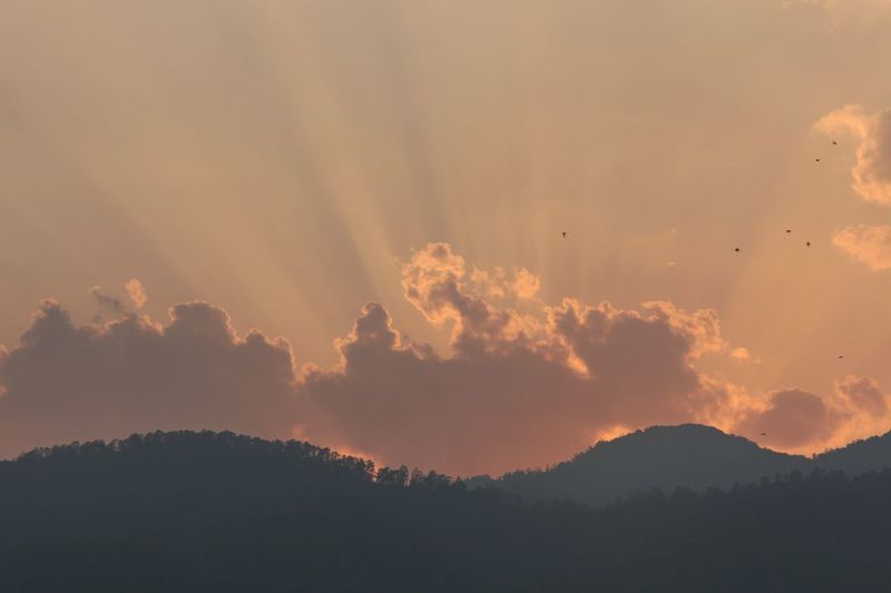 View of silhouetted mountains against cloudy sky at dawn