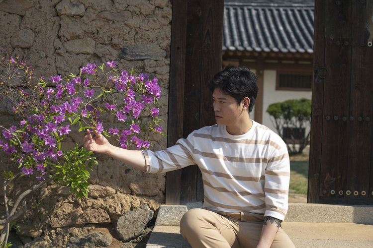 Full length of young man against purple flowering plants