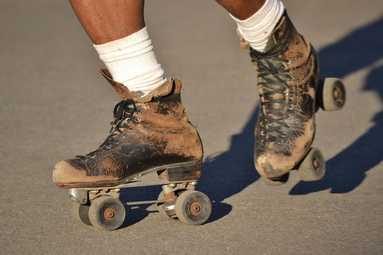 Low section of skater with messy roller skates skating on road