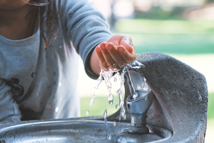 Midsection of girl at drinking fountain