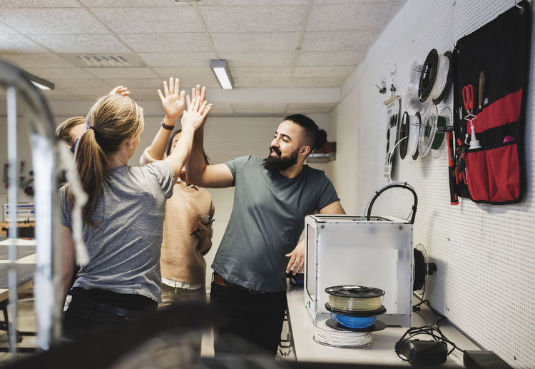 Engineers high fiving in workshop at creative office