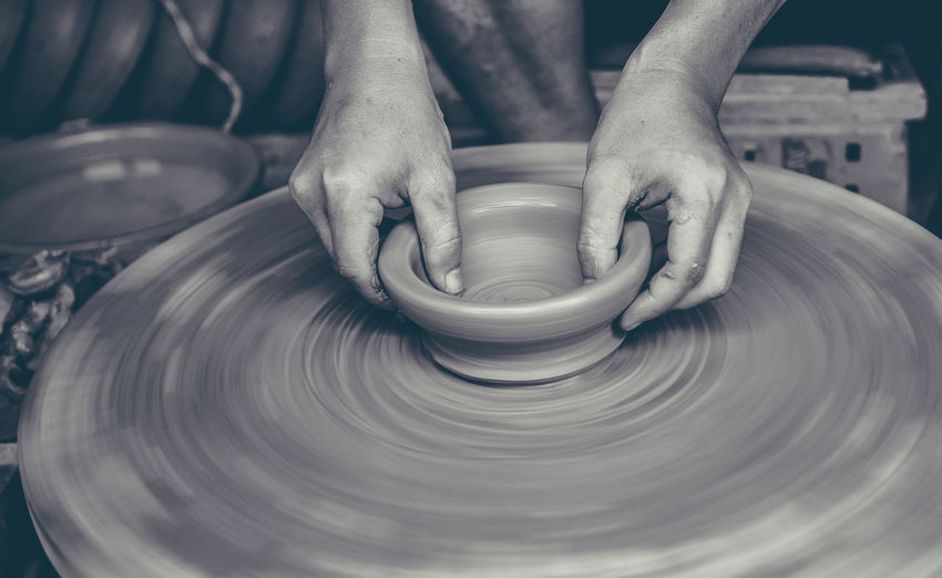 Cropped hands of potter making pot on pottery wheel