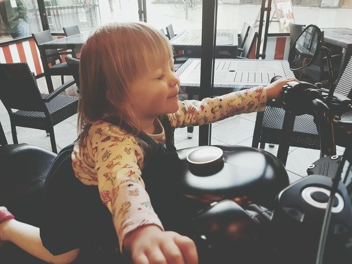 Happy girl sitting on motorcycle in restaurant
