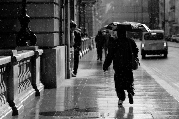 Full length of woman walking on wet street during rainy season