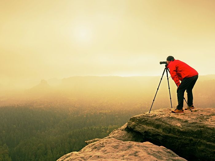 Professional photographer work on mountain peak. nature photographer takes photos with mirror camera