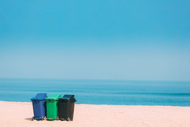 Garbage can on beach against sky
