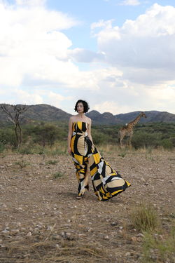 Woman in dress walking on field against sky