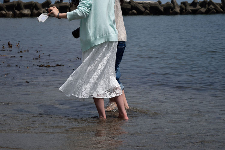 Midsection of friends wading in sea