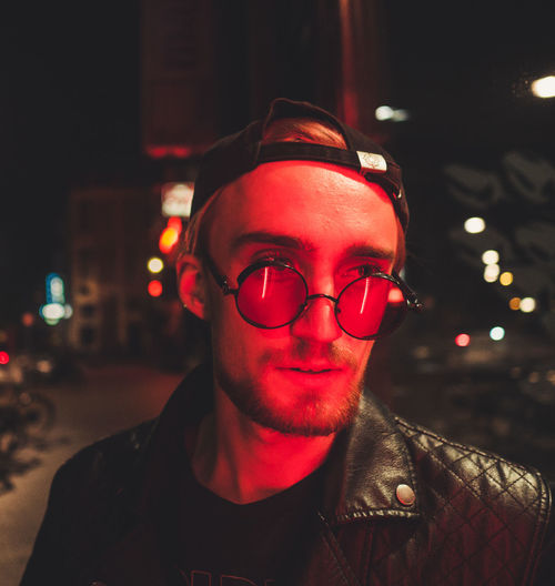 Young man wearing eyeglasses in illuminated city at night