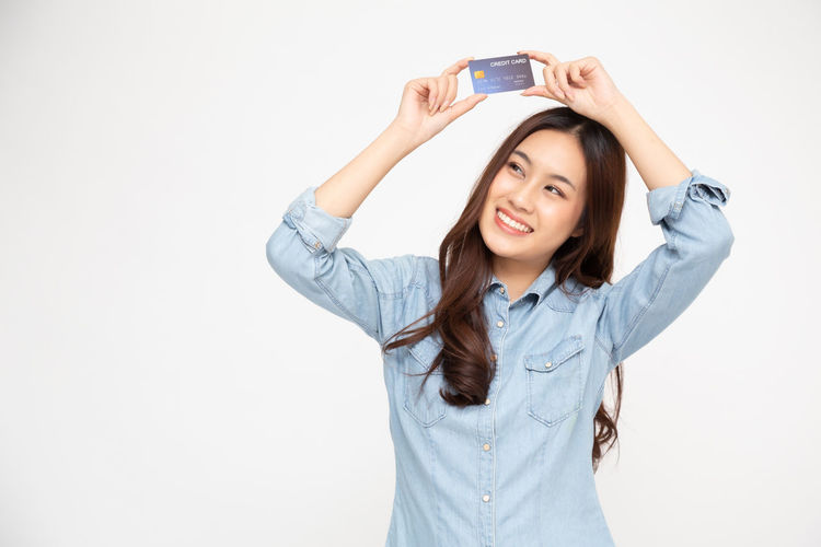 Portrait of smiling young woman using phone against white background