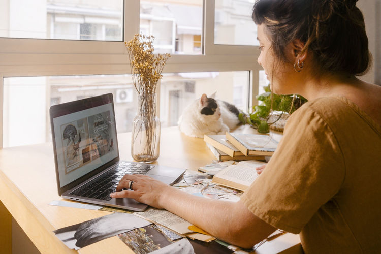 Freelance graphic designer working on laptop at desk in home