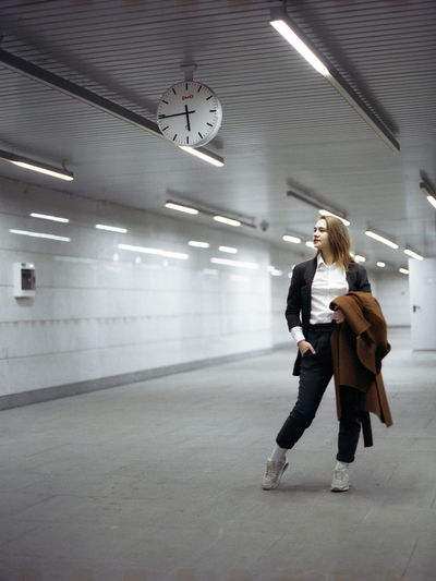 Full length of woman looking away while posing in illuminated underground walkway