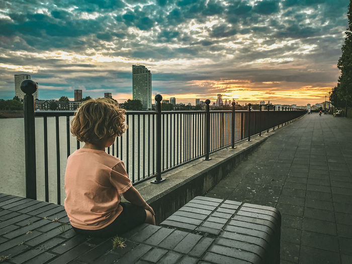 Boy contemplating sunset over london's skyline.  long road ahead