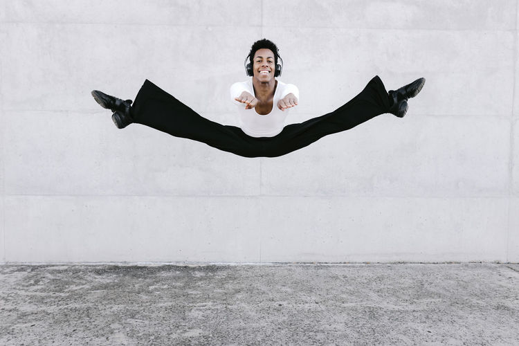 Male dancer practicing splits in mid-air against wall