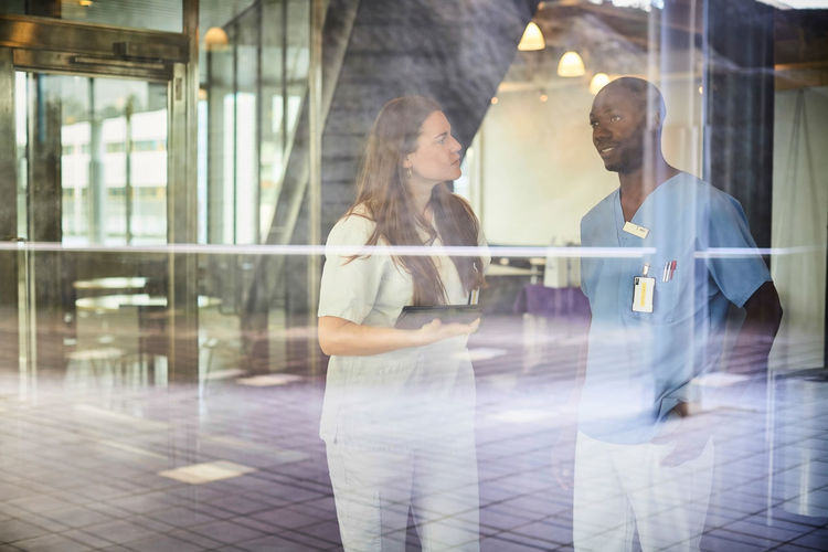Nurses discussing seen through window glass at hospital