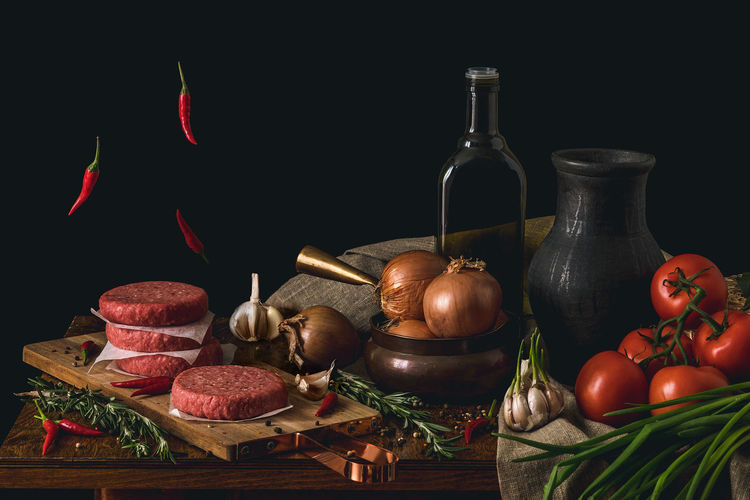 Meat and vegetables on table against black background