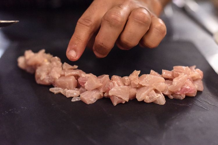 Cropped hand of woman arranging meat on slate at home