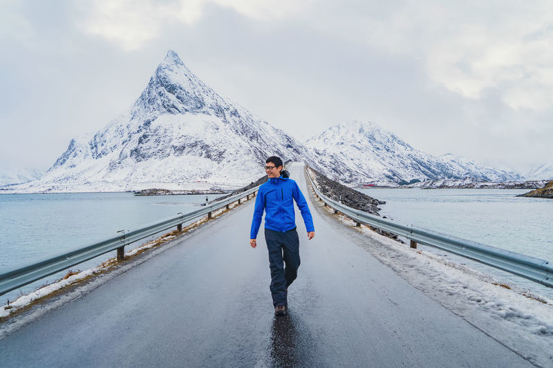 Full length of man walking on bridge over river during winter