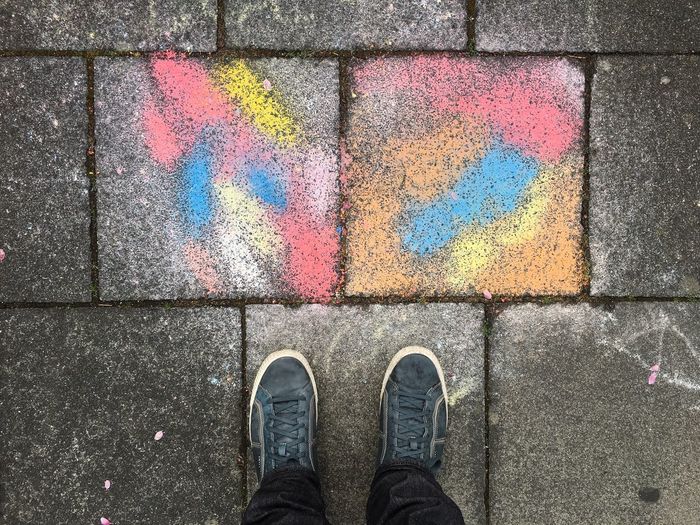 Low section of man standing by colorful paved footpath