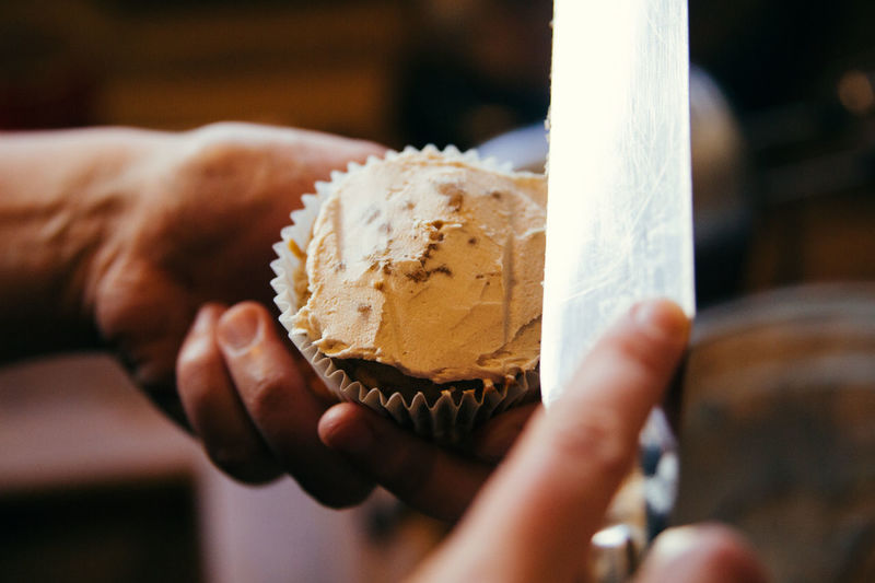 Close-up of person icing cupcake