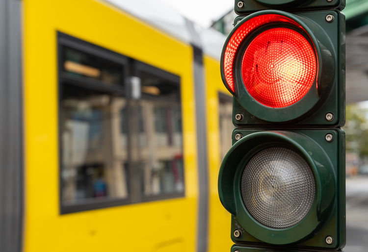 Close-up of traffic light against yellow tram