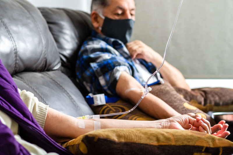 Midsection of man and woman with iv drip on hand in hospital