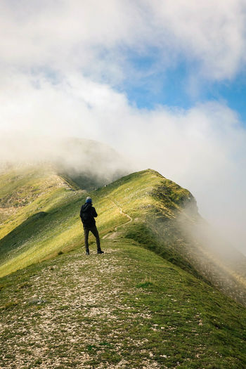Hiker standing on mountain against sky during foggy weather