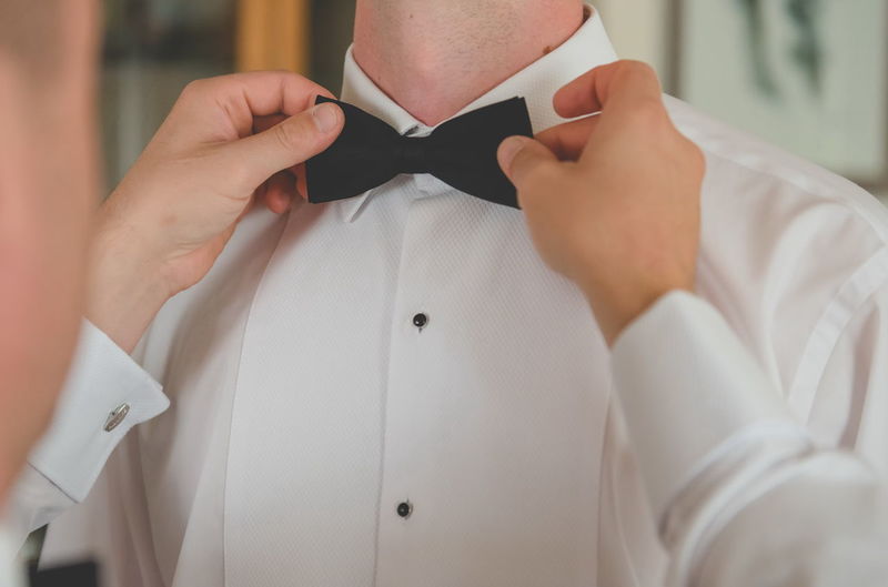 Cropped image of man adjusting bow tie on friend