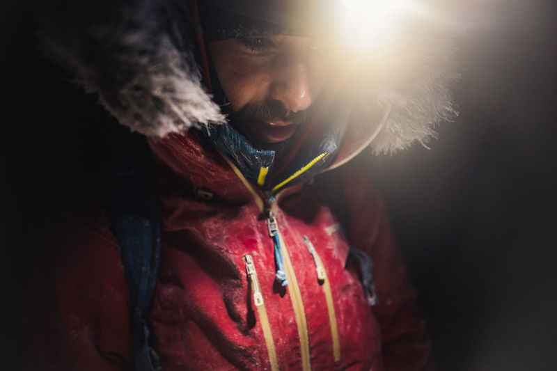 A man with frost and ice on his jacket with headlamp