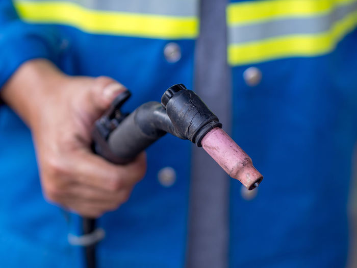 Midsection of person holding fuel pump