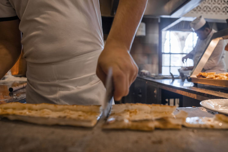 Chef cutting turkish pide into slices on table at restaurant