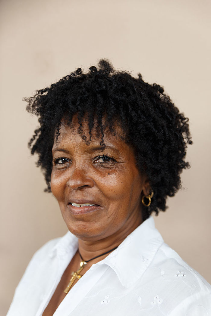 Close-up portrait of smiling mature woman against wall